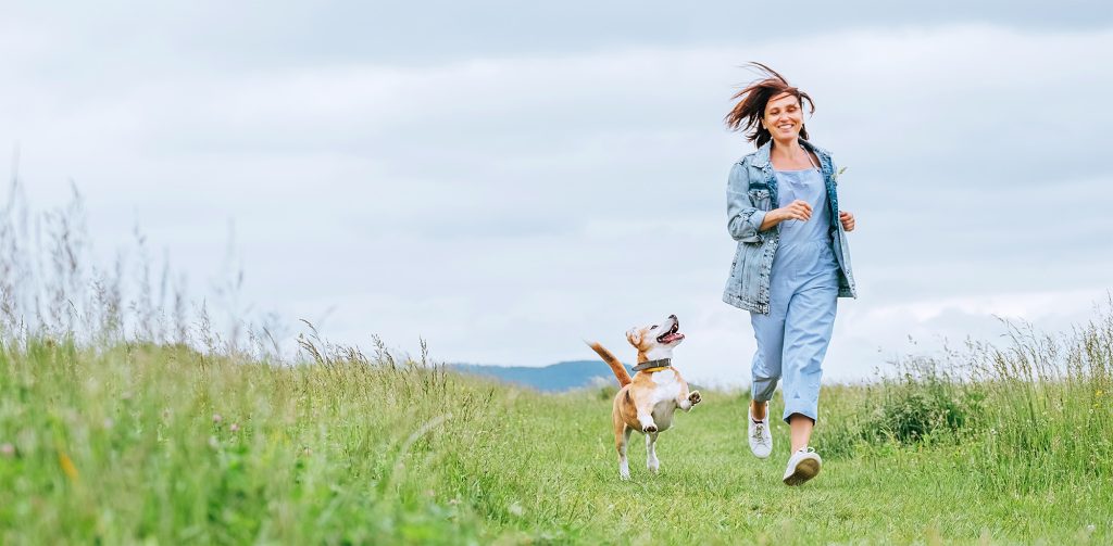 Happy smiling jogging female with fluttering hairs and her beagl Healthy active dog